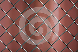 Close-up of isolated painted simple geometric black iron metal wire chain link fence eon dark red background. Fence, protection an