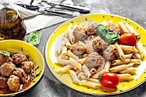 Close-up of Italian pasta with tomato sauce and meatballs on a yellow plate and a gray background. Food recipe background. Close