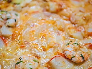 Close up of an Italian pizza with zucchini shrimp crabmeat, mozzarella and tomato