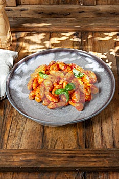 Close up of Italian potato Gnocchi with tomato sauce and fresh basil on gray plate on wooden background
