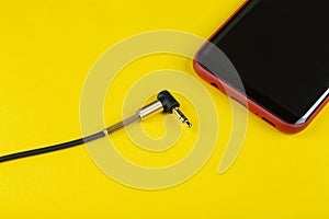 Close-up Jack plug and a cable with phone on a yellow background