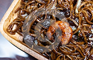 Close up of Jajangmyon serving on wooden plate. Chinese-style Korean noodle dish topped with a thick black sauce made of chunjang