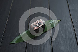 Close up of Japanese Gunkan Maguro Maki Sushi with tuna and tobiko caviar on bamboo leaf on black wooden board