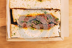 Close up of Japanese medium rare Wagyu sandwich served in wooden box