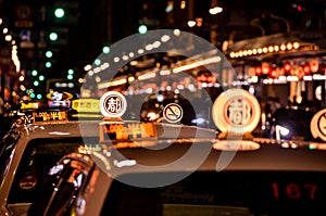 Close up of Japanese taxi car signs at night with blurry lights in Kyoto..Translation: ``Kyoto city taxi. 5000 yen mimimum fee