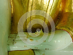 Close up of jasmine flowers on hand of golden buddha statue, Myanmar