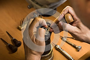 Close-up of a jeweler's hands fixing a gemstone in a silver pendant