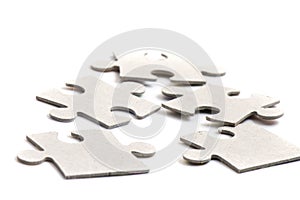 Close-up on jigsaw puzzle pieces, blank white paper jigsaw puzzle elements linked together and separate,