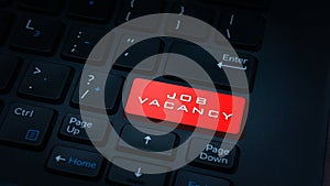 Close-up JOB VACANCY button with red color on a dark laptop keyboard technology background.