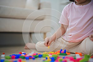 Close up. Joyful Asian girl happy and smiling playing colorful Lego toys, sitting on the living room floor, creatively playing