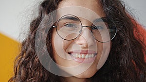 Close-up of joyful Asian lady wearing eyeglasses smiling looking at camera indoors