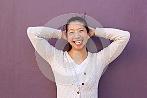 Close up joyful asian woman standing with hands behind head