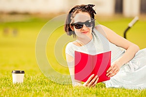 Close-up of joyful beautiful female sitting with book on grass