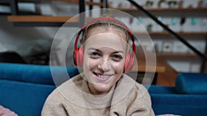 Close-up joyful teenage girl enjoying music in headphones looking at camera singing smiling. Portrait of cheerful pretty