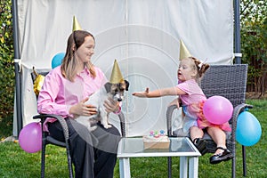 Close-up of Joyful two girls sisters celebrating their dog\'s birthday