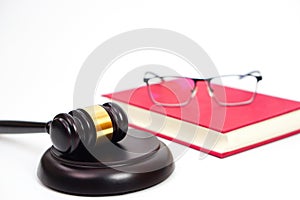 Close up of judge gavel or hammer and blurred glasses on the law book placed behind.