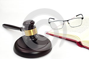 Close up of judge gavel or hammer and blurred glasses on the law book placed behind. Law, judiciary concept.