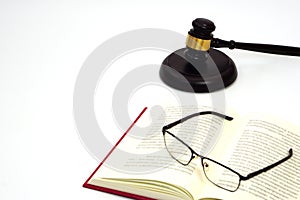 Close up judge gavel or hammer placed behind and blurred glasses with law book. Law, judiciary concept.