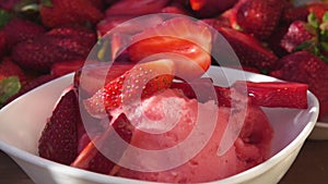 Close-up of the juicy strawberry halves falling on the strawberry ice-cream