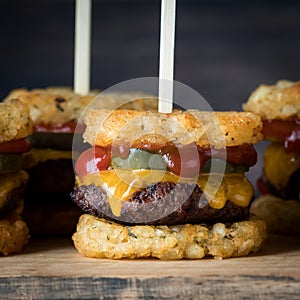 A close up juicy tater beef appetizer skewers against a dark background.