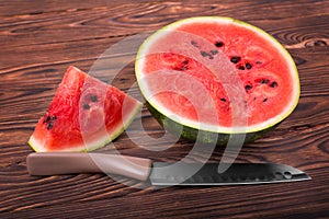 Close-up of juicy watermelon on the wooden background and a big knife is right near it. Summer watermelon