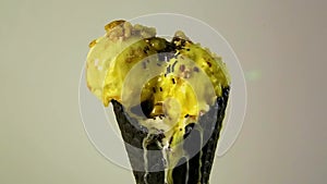 Close-up juicy yellow balls of ice cream in chocolate waffle cup with chocolate topping and nuts have pouring caramel topping