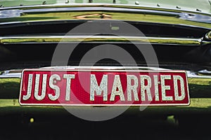 Close up of `just married` license plate with red background attached to chromed car grille. Wedding day concept.