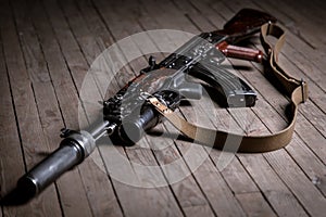 Close up of  Kalashnikov assault rifle with suppressor on wooden background