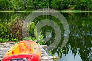 Close up of kayak on pier beside large forested lake