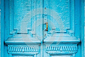 Close-up keyholes with curtains and a handle on the blue many times painted cracked double-barreled wooden vintage door