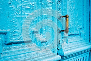 Close-up keyholes with curtains and a handle on the blue many times painted cracked double-barreled wooden vintage door