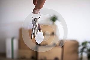 Close-up of the keys of the new empty apartment with moving boxes on the floor