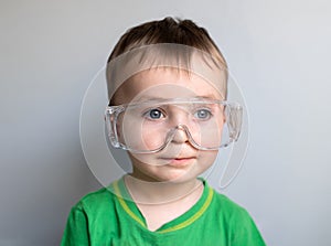 Close up the kid face wearing a protective glasses. Child face in safety goggles