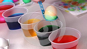 Close up of kid hands coloring easter eggs with egg dye. Bright colorful glasses