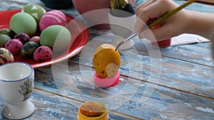 Close up of kid hands coloring easter eggs with egg dye. View from above