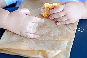 Close up kid hands holding croissant.