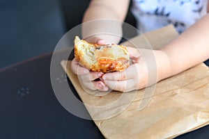 Close up kid hands holding croissant.