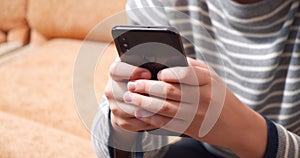 Close up of kid hands holding smartphone while playing video game or typing message. Online games and leisure concept