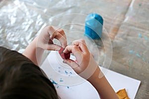 Close up of kids hands molding colorful clay on the wooden table. Selective focus, preschool, kindergarten, day care,