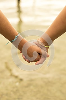 Close up of kids holding hands on beach concept