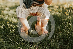 Close up of kids legs on a grass. Baby feeling grass for the first time. Family concept