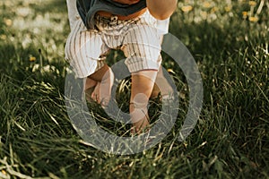 Close up of kids legs on a grass. Baby feeling grass for the first time. Family concept