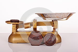 Close up of 1kilogram and 500gm rusty standard metric weights made of iron and antique gold weighing scales on white background.