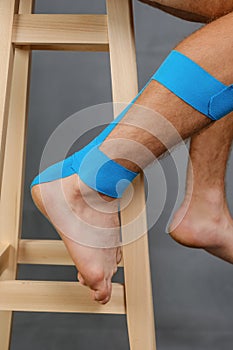 Close-up kinesiology tape applied to injured calf and heel of a white male