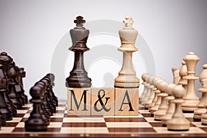 Chess Wooden Blocks With Mergers And Acquisitions Text photo