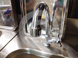 Close-up of a kitchen sink with a mixer on the background of a kitchen pan, an old faucet with reflection, selective focus, blur