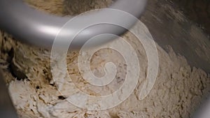 Close-up of kneading dough in production mixer. Stock footage. Spiral kneader kneads fresh dough for baking in bakery
