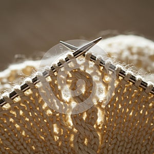 Close-up of knitting in progress with cream-colored yarn on metal needles. The fabric