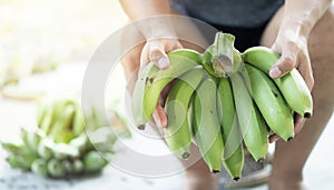 Close up of labor's hands holding green banana for sell. Selective focus