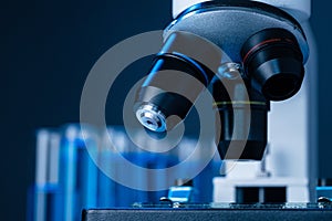 Close up of laboratory microscope with set of test tubes with blue liquid